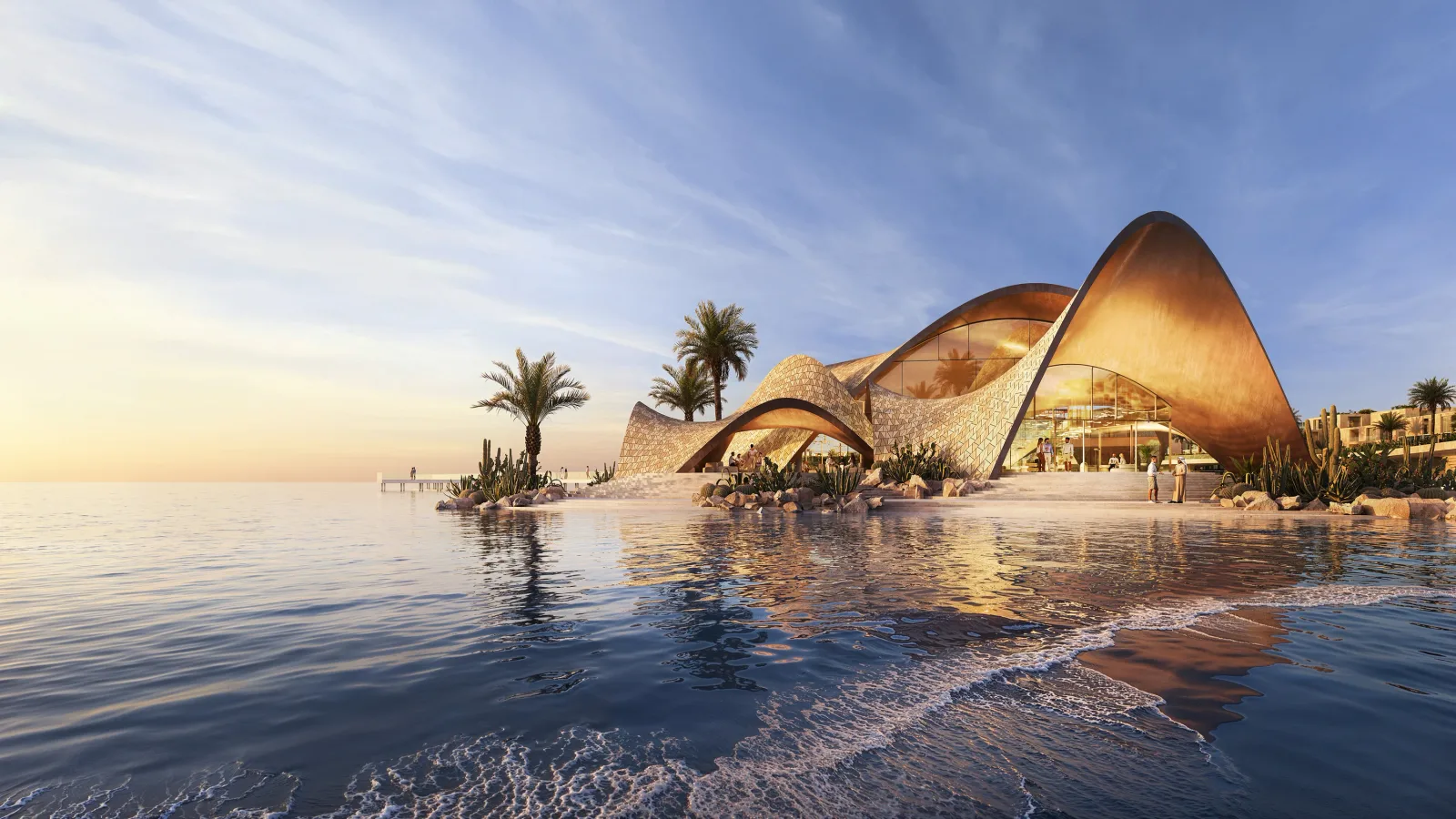 The wave-form beach club pavilion at sunset, its patterned shell rising from the shoreline