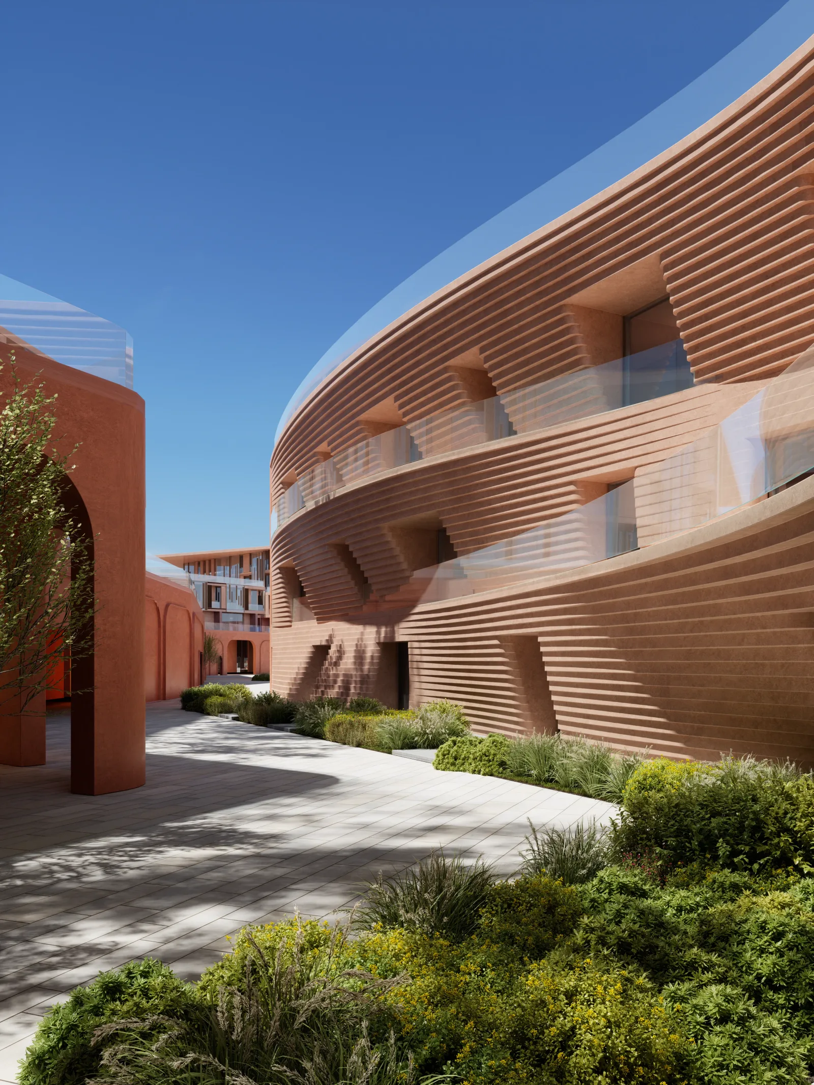 A planted courtyard beside a drum-shaped ribbed facade, with an arched terracotta screen opposite